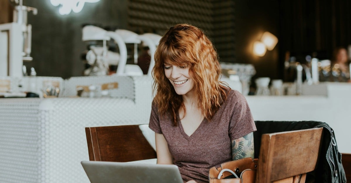 smiling woman working remotely in a cafe